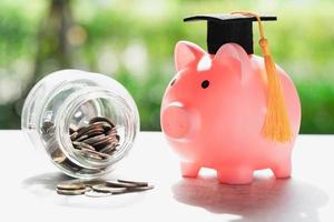 Save money coins in grass jar with piggy bank and graduation cap, Business finance education concept. photo