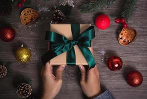 Hand holding Christmas present gift set on wooden table background. photo