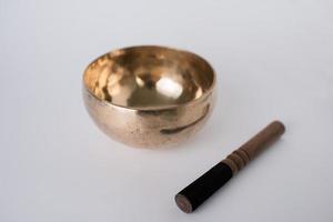 Tibetan Meditation Singing Bowl and wooden mallet next to it. White background. Chakra healing photo