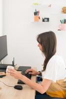 Adult woman working at home with her computing while taking a coffee photo