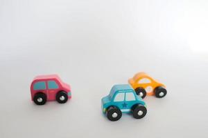 Tres pequeños coches de juguete de color rosa, amarillo y azul con fondo blanco. foto
