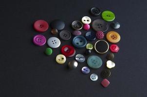 forma de corazón con botones de colores en un fondo negro foto