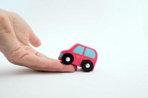 Close up of a caucasian hand helping a pink car to go up.White background. Conceptual for help. photo