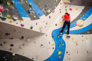 Active young climber woman climbing on indoor climbing wall photo