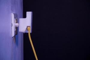 Extensor wifi en toma de corriente en la pared con cable ethernet enchufado foto