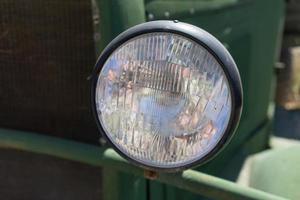 Old car headlight on a green background. photo