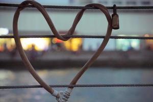 Heart-shaped padlock locked metal cables during twilight time