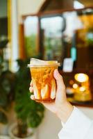 hand holding caramel macchiato coffee glass photo
