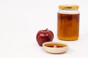 Manzana roja y tarro de miel cuenco de miel aislado sobre un fondo blanco.