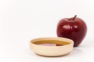 Manzana roja y cuenco de miel aislado sobre un fondo blanco.