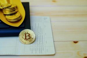 Close up of gold bitcoin coins on bank passbook with a golden shovel on wooden table photo