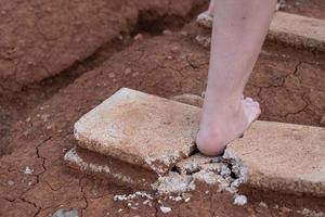 Photo close up of shards of a broken concrete block at woman barefoot at the walking
