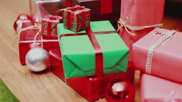 scatola regalo di natale sul tavolo e luci ornamenti natale festeggia il nuovo anno nel soggiorno di casa. video