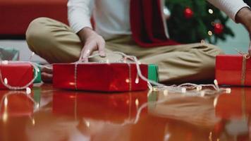 Hombre asiático haciendo una caja de regalo en la sala de estar de casa. video