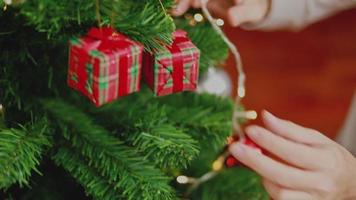 homem asiático segurando uma pequena caixa de presente Natal decorar a árvore de Natal comemora o ano novo na sala de estar em casa. video