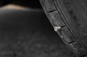 Close up button head needle metal screw nail stuck to puncture into wheel tire photo