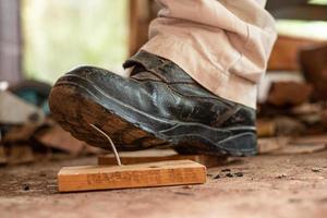 Worker in safety shoes stepping on nails on board wood In the construction area photo