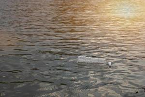 Botella de plástico de desecho usada flotando en el agua en un canal, enfoque ecológico concepto ambiental y de contaminación foto