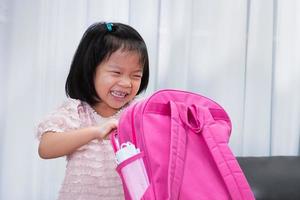 Asian girls are having fun packing their bags to school. Kindergarten students with pink school bags. photo