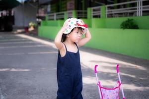 linda chica lleva un sombrero para protegerse la cara del sol mientras camina. niños de 2-3 años. foto