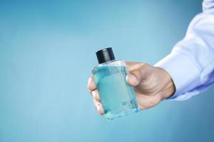 hand hold a mouthwash liquid container against blue background photo