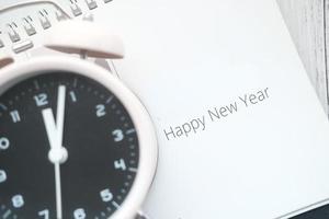 Feliz año nuevo texto en calendario con reloj en mesa foto