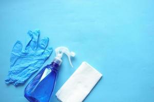 cleaning paper, bottle and hand gloves on blue photo