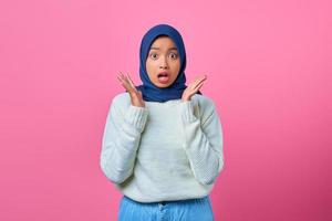 Portrait of surprised young Asian woman looking camera on pink background photo