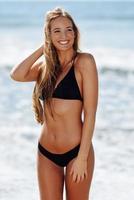 joven mujer rubia con hermoso cuerpo en traje de baño sonriendo en una playa tropical. foto