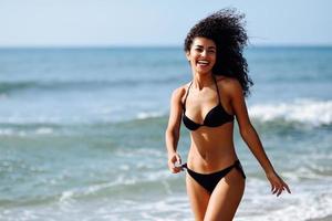 Young arabic woman with beautiful body in swimwear smiling on a tropical beach.