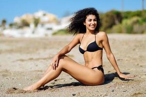 Mujer árabe con hermoso cuerpo en bikini tumbado en la arena de la playa foto