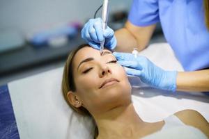 maquillaje permanente para cejas de mujer hermosa en un salón de belleza. tratamiento de micropigmentación. foto