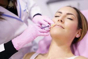 médico inyectando ácido hialurónico en el rostro de una mujer como tratamiento de rejuvenecimiento facial. foto