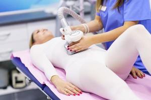 Woman in special suit having a anti cellulite belly massage with spa apparatus photo