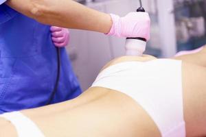 Woman receiving anti-cellulite treatment with radiofrequency machine in a beauty center. photo