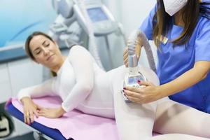 Woman in special white suit having a anti cellulite massage with spa apparatus photo