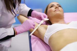 Doctor painting on the armpit of her patient, the area to be treated for hyperhidrosis.