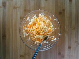 Carrots with cabbage in a glass bowl, top view, salad for lunch, wooden background photo