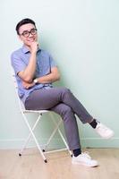 Young Asian buisnessman sitting on chair in green background photo