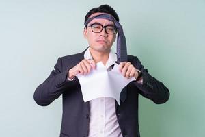 Young Asian businessman posing on green background photo