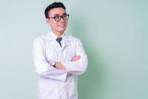 Asian doctor standing on green background photo