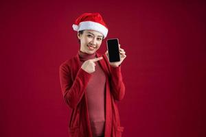 joven, mujer asiática, llevando, sombrero de navidad, en, fondo rojo foto