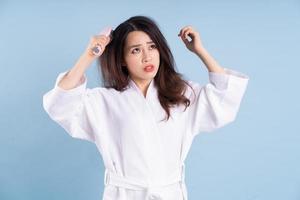 Young Asian woman wearing bathrobe on blue background photo