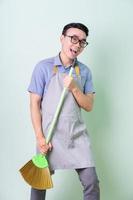 Young Asian man wearing apron posing on green background photo