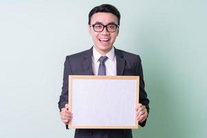 Young Asian businessman posing on green background photo