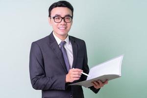 joven empresario asiático posando sobre fondo verde foto