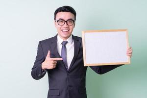 Young Asian businessman posing on green background photo