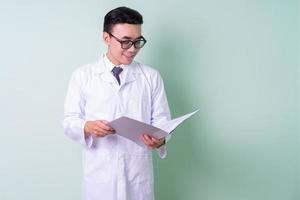 Asian doctor standing on green background photo