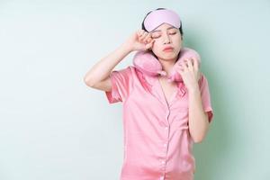 Young Asian woman wearing pajamas on green background photo