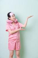 Young Asian woman wearing pajamas on green background photo
